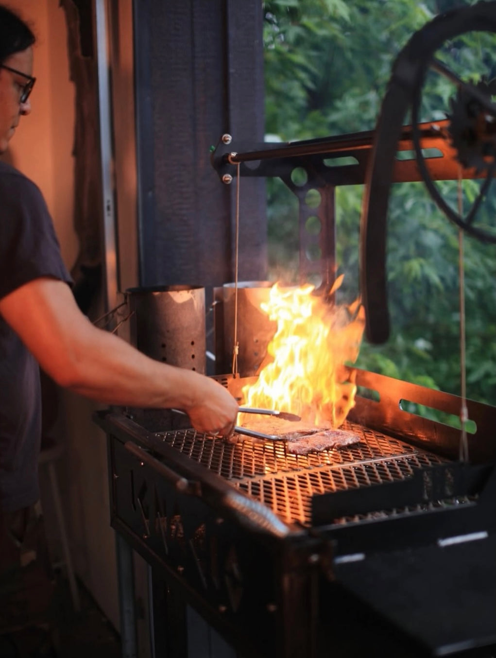 Person grilling outdoors with flames visible
