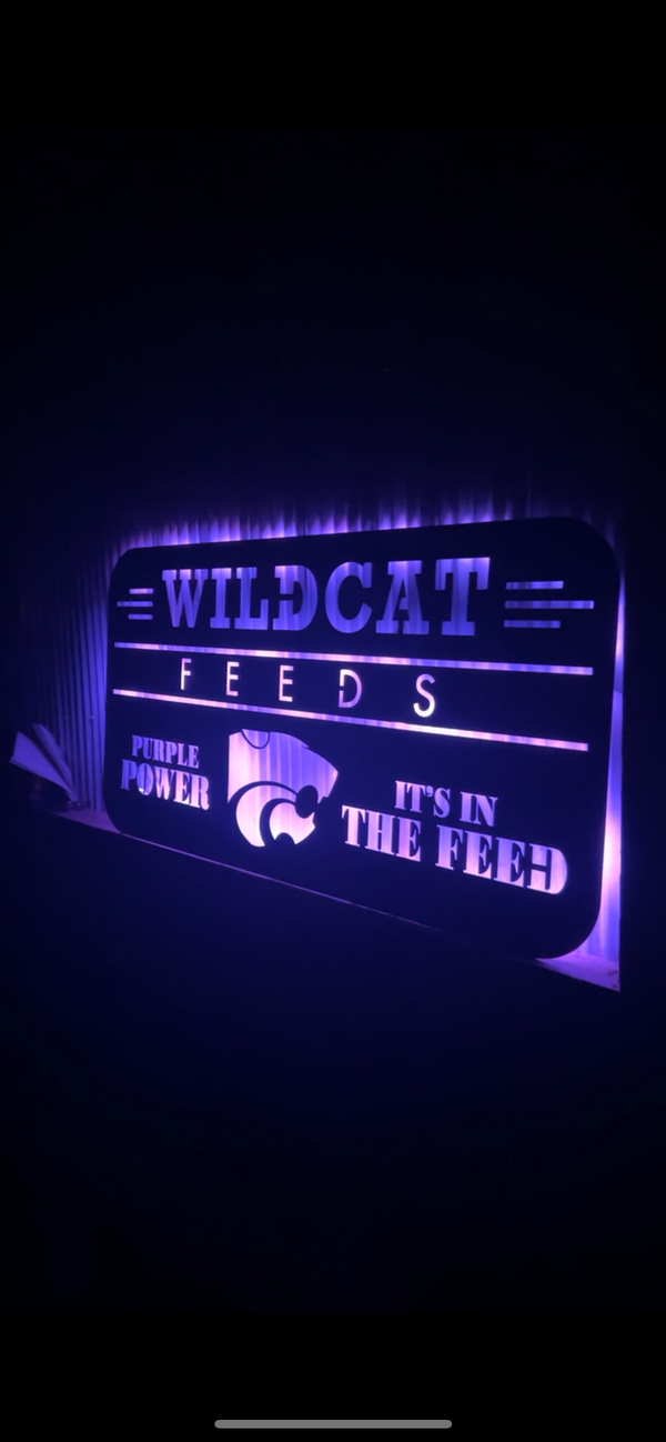 Wildcat Feeds sign with purple lighting on a dark background