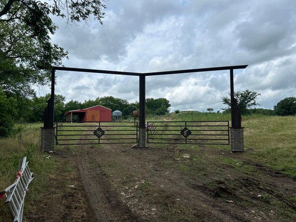 Farm gate leading to a field with a barn under a cloudy sky