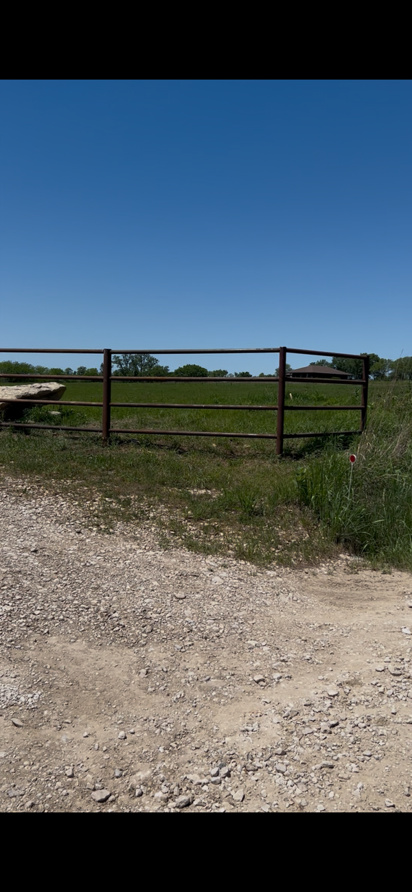 Gravel path leading to a metal gate with a clear blue sky